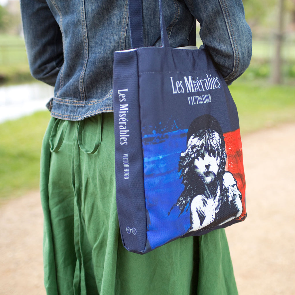 Les Misérables Navy Tote Bag by Victor Hugo featuring Cosette over French flag design, by Well Read Co. - Model with bag
