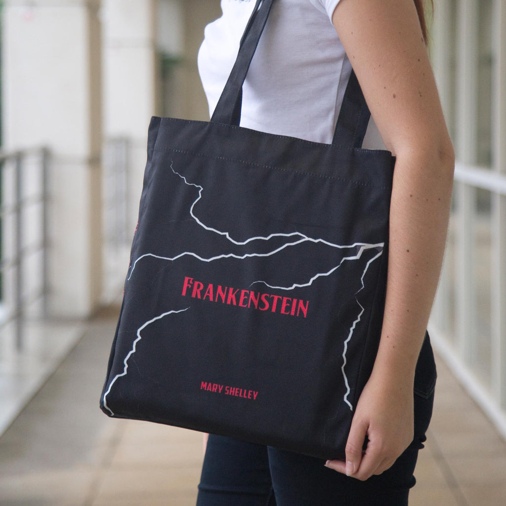 Frankenstein Black Tote Bag by Mary Shelley featuring Lightning Flash design, by Well Read Co. - Model with bag