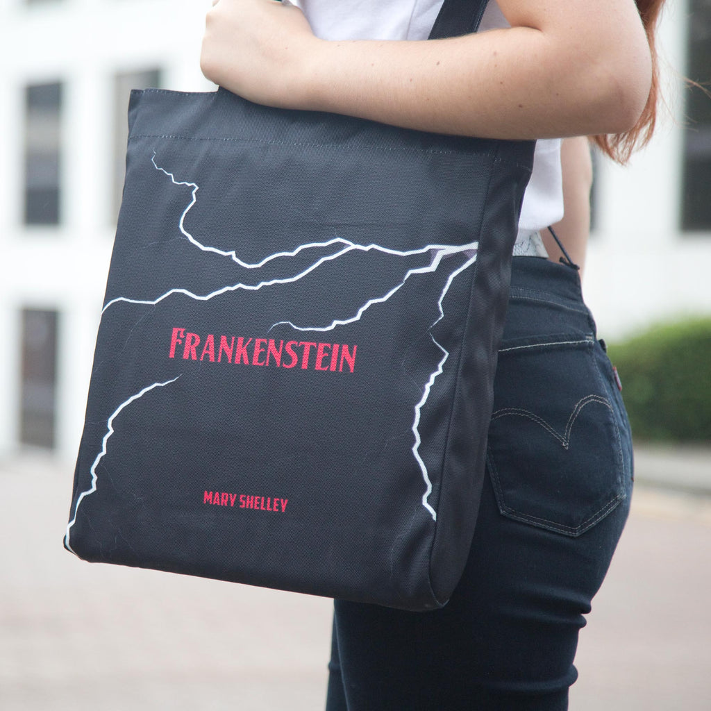 Frankenstein Black Tote Bag by Mary Shelley featuring Lightning Flash design, by Well Read Co. - Model Standing with Bag